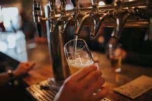 A beer is poured from silver bar taps inside a pub.