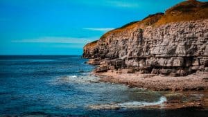 A rocky outcrop into a sky blue sea at Winspit Quarry, Dorset