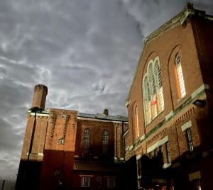 Red brick buildings of Dorchester Prison against a cloudy grey sky