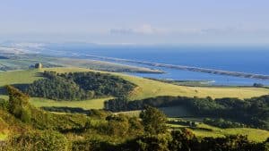 a view of chesil beach and weymouth, with the church at abbotsbury in the distance