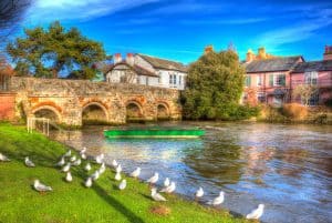 River Avon Christchurch Dorset England UK with bridge and green boat